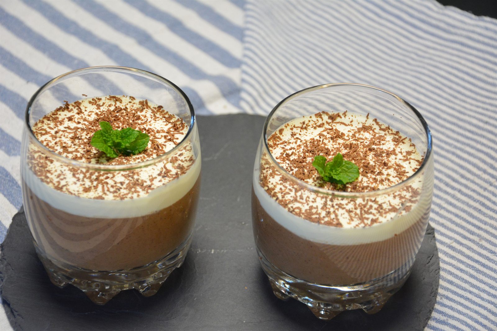 Två glas hemgjord chokladmousse toppad med vispgrädde, riven choklad och färsk mynta