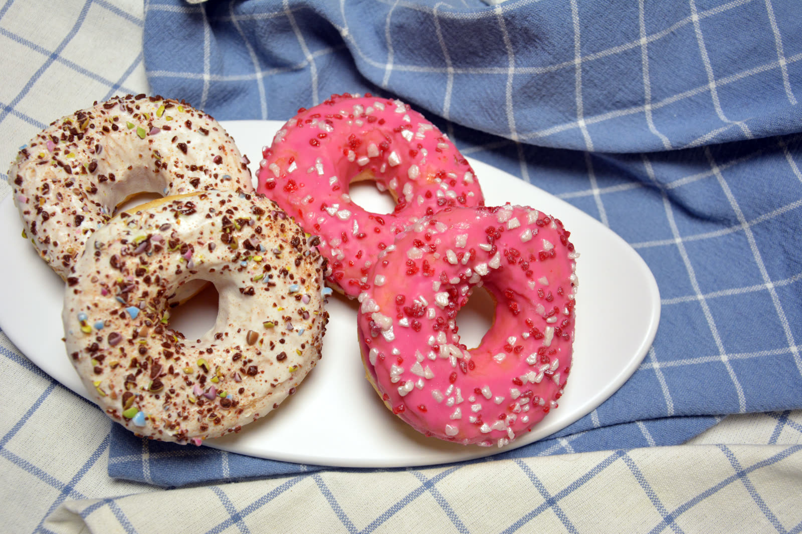 Hemmagjorda donuts med rosa och vit glasyr och färgat strössel på ett fat