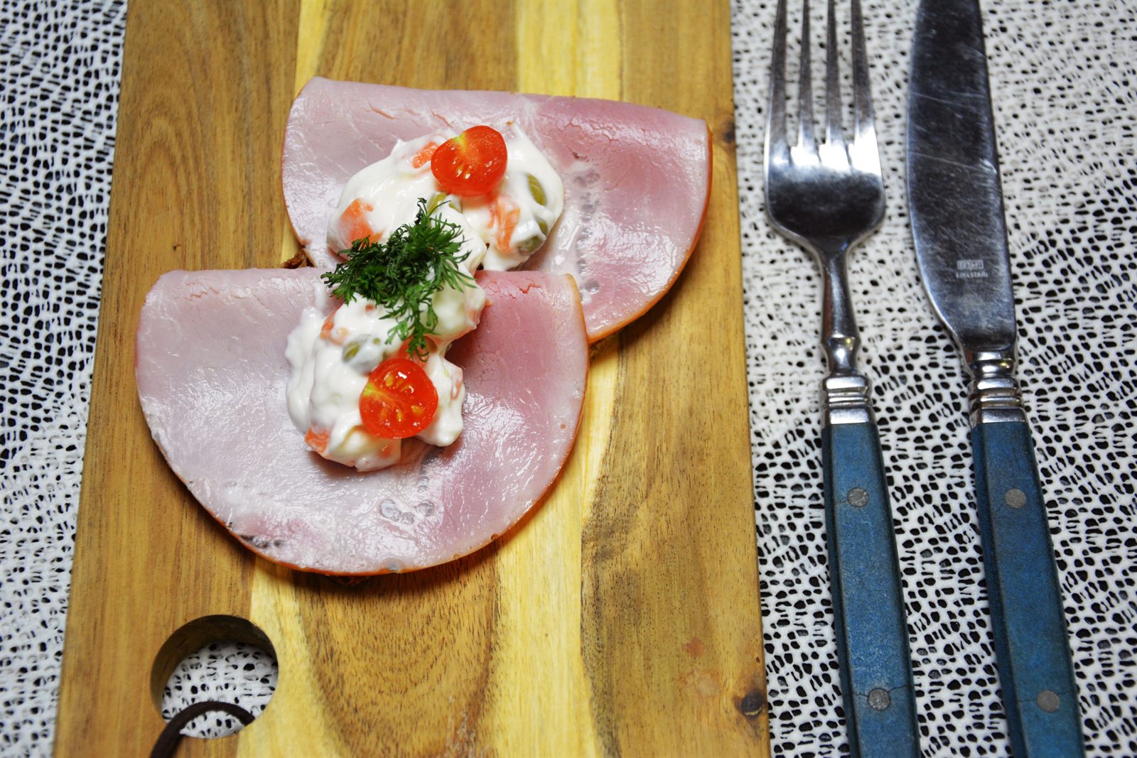 Legymsallad med morotstärningar och gröna ärtor på två vikta skivor kokt skinka på rågbröd, garnerad med en halv körsbärstomat och dill